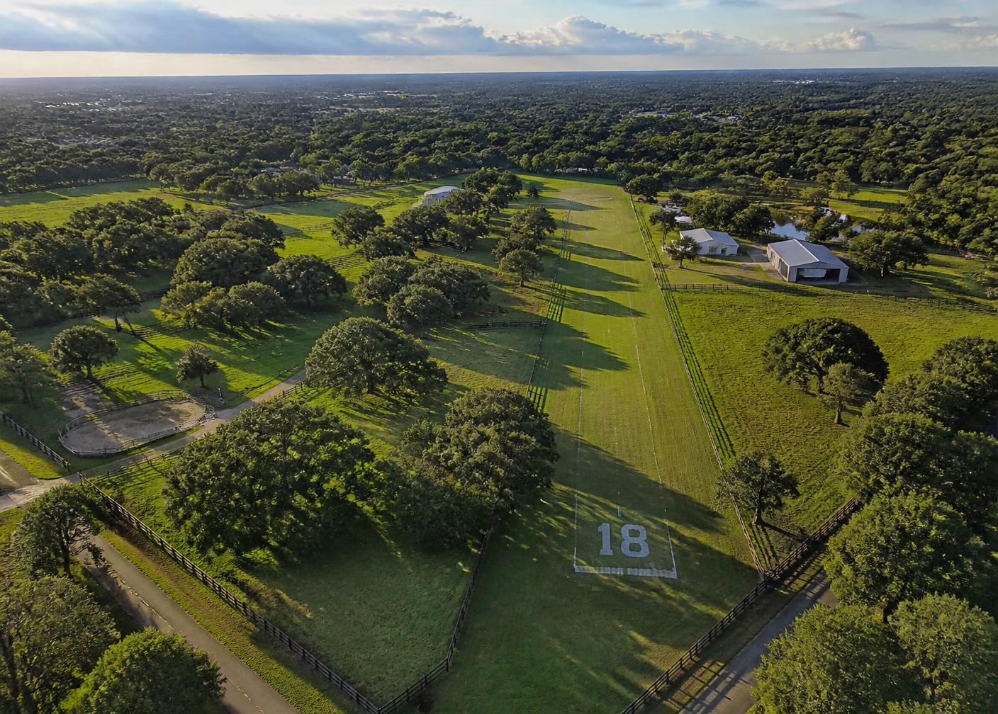 Aerial view of fenced acreage and grass airstrip in Central Florida